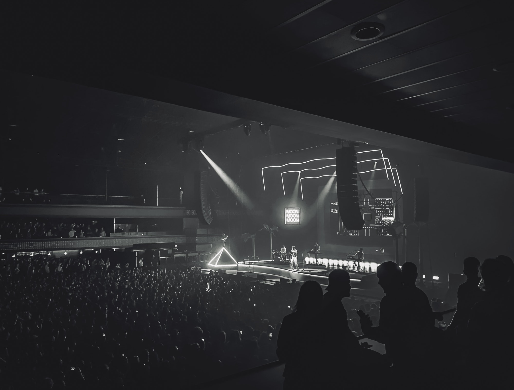 Group of friends talking together at a concert in silhouette, concert and large crowd in background